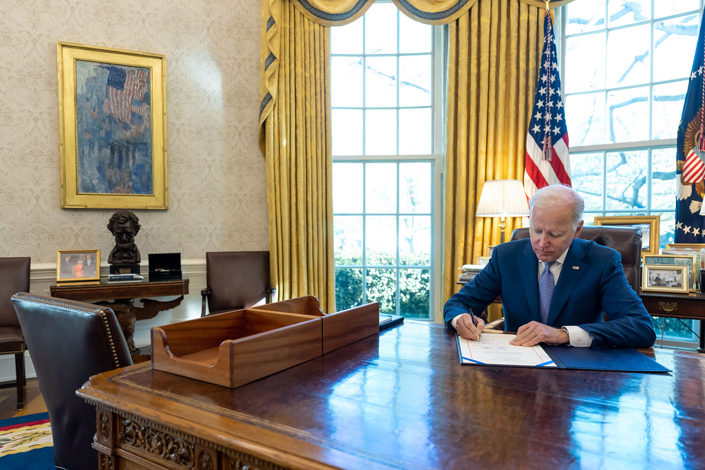 President Joe Biden sitting at the resolute desk in the Oval Office, signs H.J. Res. 7, “Relating to a National Emergency Declared by the President on March 13, 2020” terminating the National Emergency concerning COVID-19, Monday, April 10, 2023, in the Oval Office of the White House. (Official White House Photo by Adam Schultz)