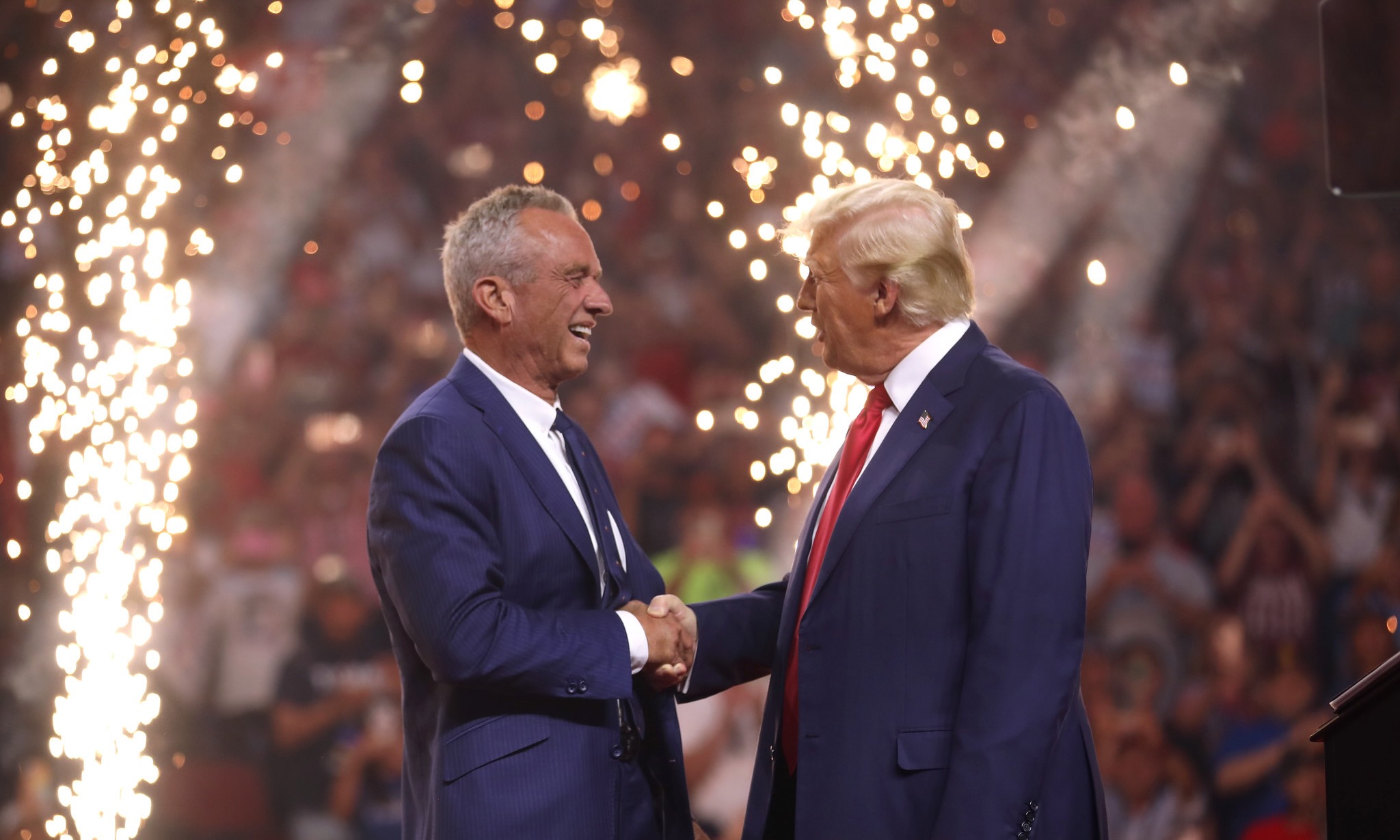 A photograph of Robert F. Kennedy Jr. and former President Donald Trump on stage in Glendale, Ariz., with fireworks behind them.