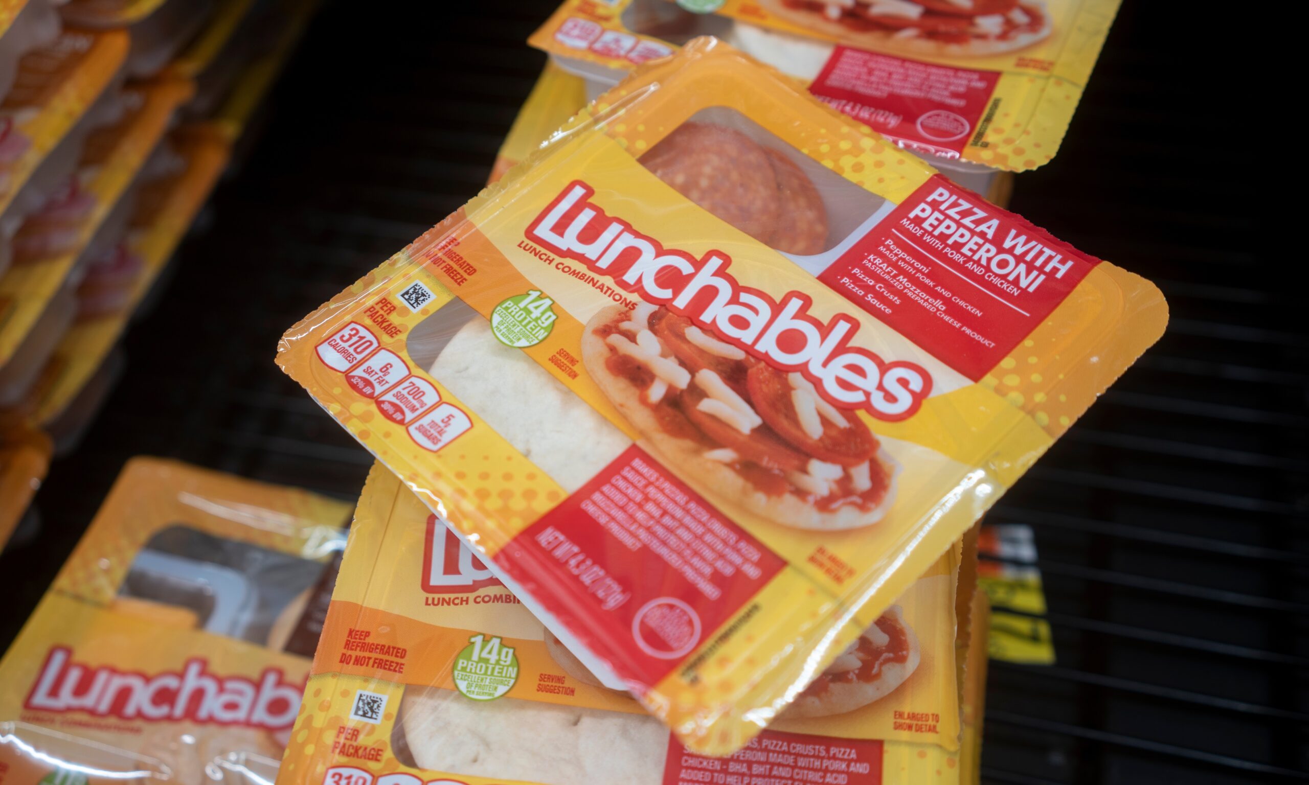 A photograph of a stack of yellow Lunchables packages. The variety is Pizza.