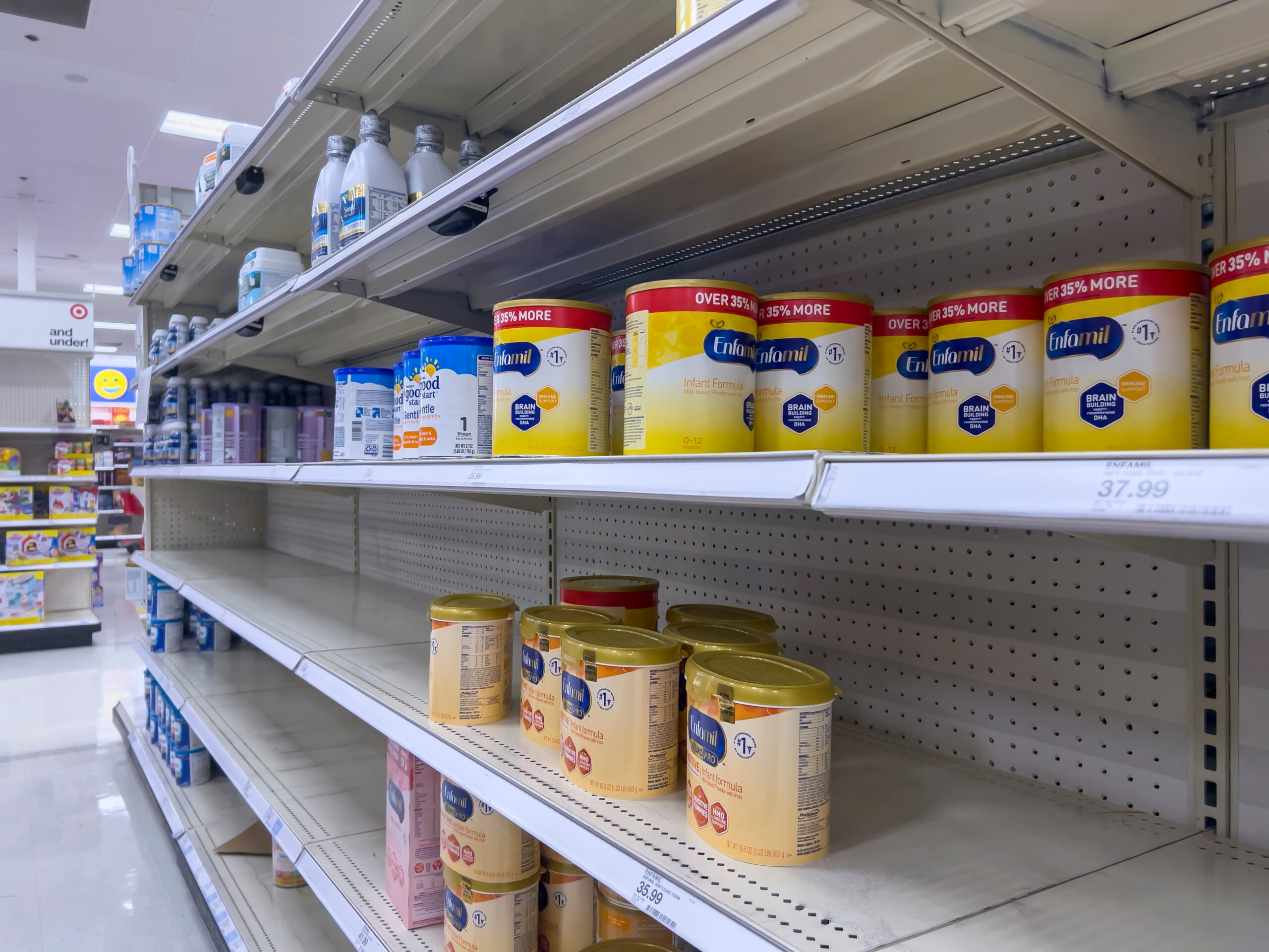 Store shelves show only some cans of Enfamil and low stocks of infant formula overall.