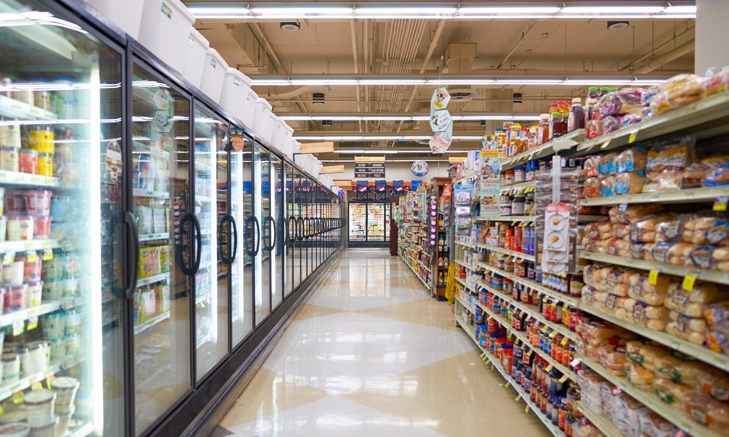 A grocery store aisle - on the left side it's a frozen section with glass doors, on the right hand side it's a bread section.
