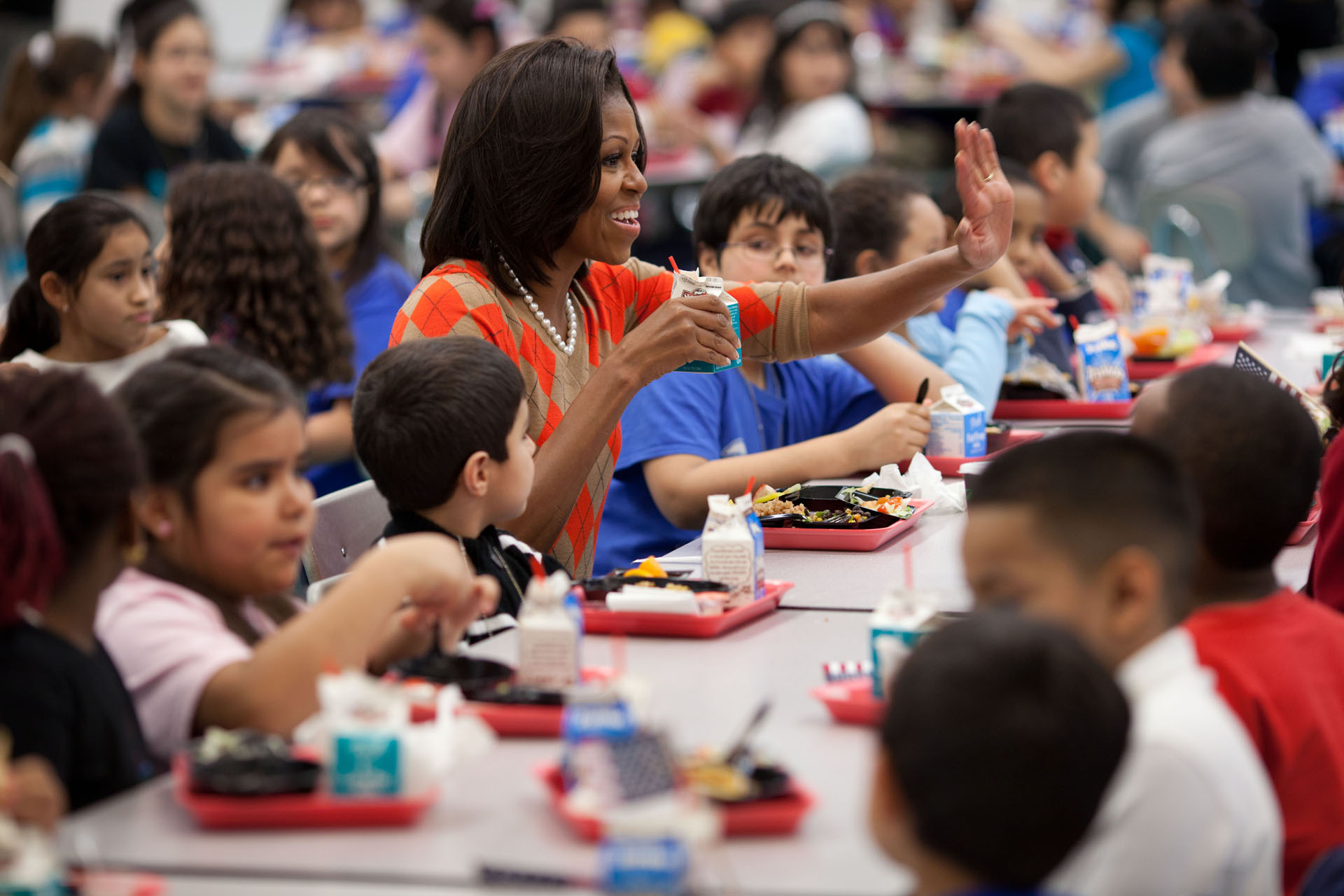 First Lady Michelle Obama eats lunch in a school cafeteria surrounded by children. (Official White House Photo by Chuck Kennedy)