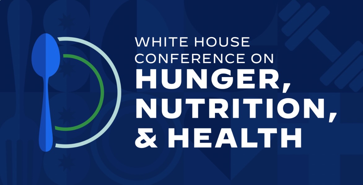 Image with a blue geometric background, with white text 'White House Conference on Hunger, Nutrition & Health'. A cartoon of a large spoon with white and green curved design is to the left of the text.