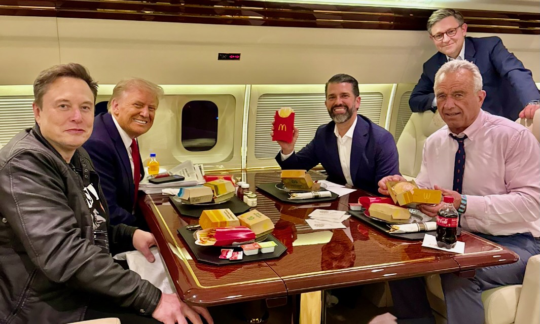 A photograph of Elon Musk, Donald Trump, Donald Trump Jr., and Robert F. Kennedy Jr. sitting with McDonald's.