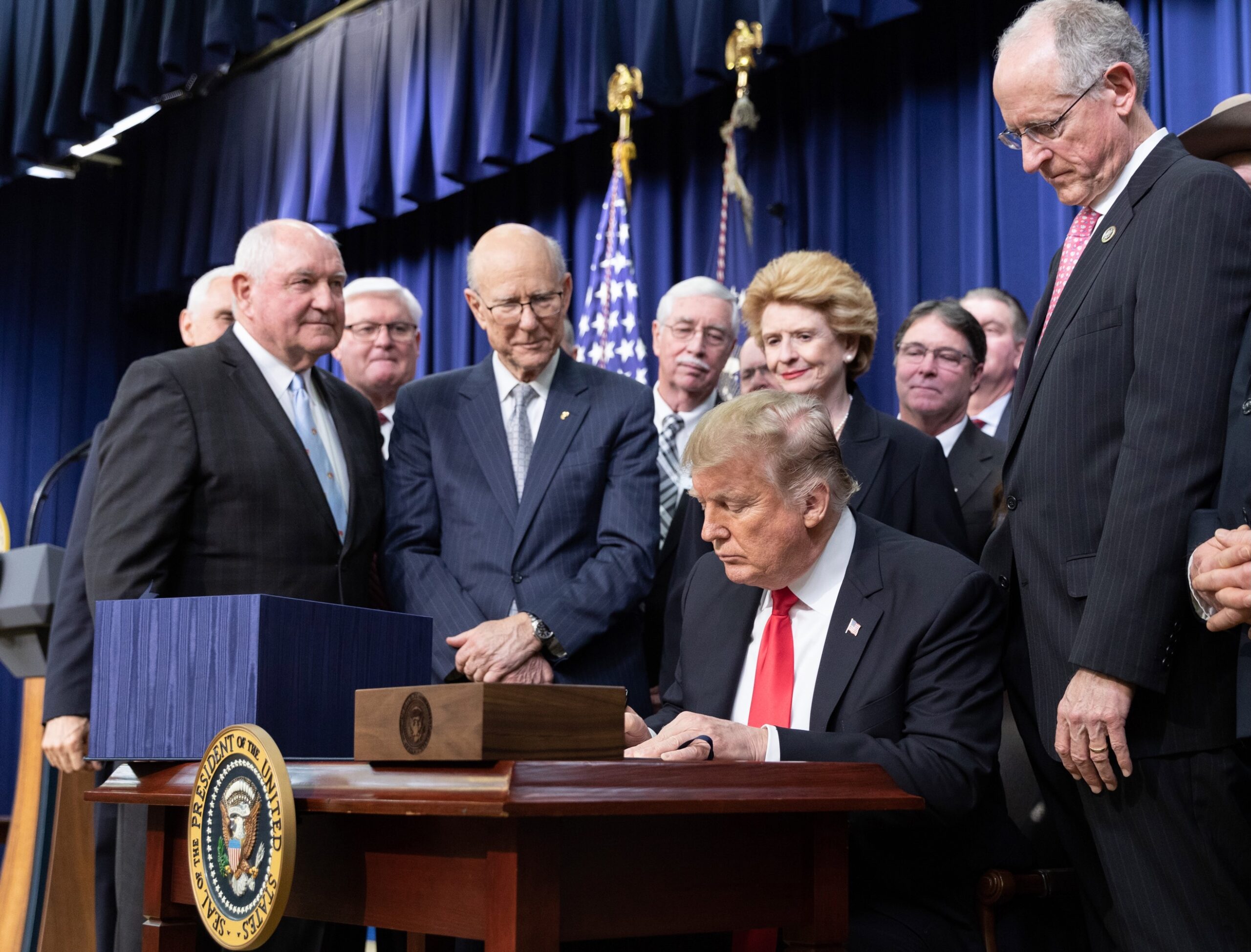 Former President Donald Trump signs the farm bill surrounded by lawmakers on both sides of the aisle.